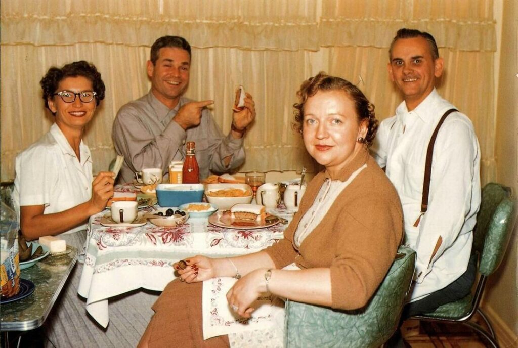 Vintage family photo: two couples sharing a meal around the kitchen table