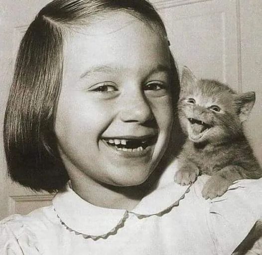 Vintage photo: a smiling girl holding a meowing kitten
