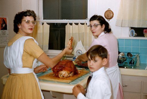 Vintage photo: two women and a boy preparing the holiday turkey in the kitchen