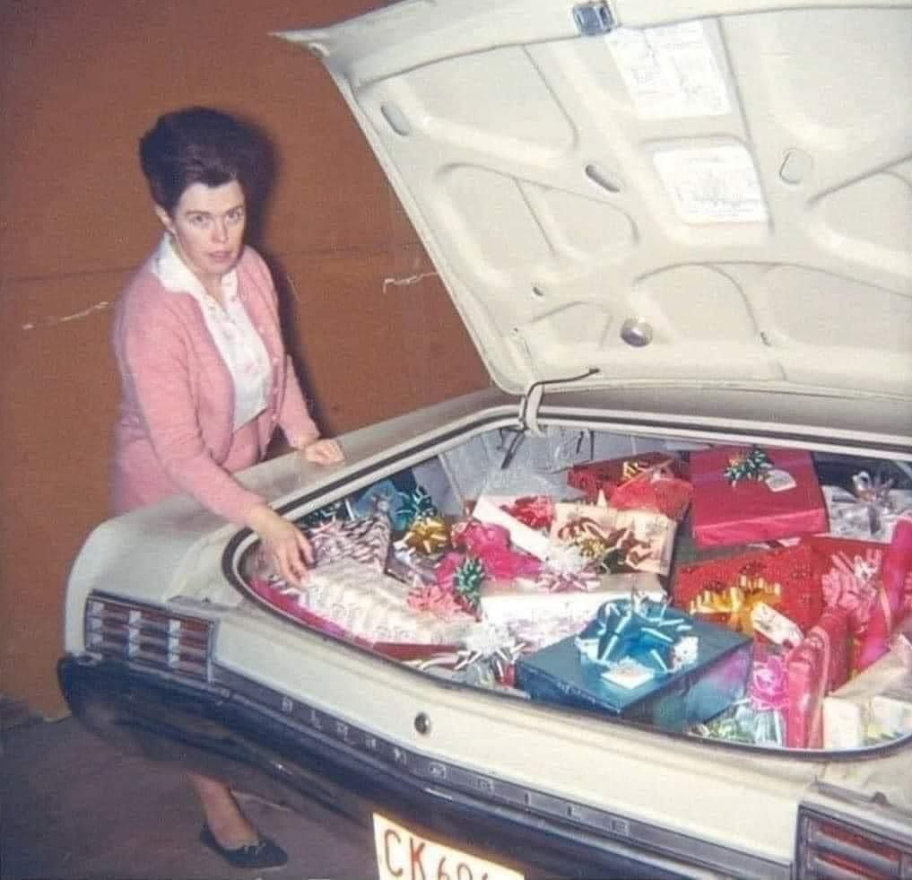 Vintage photo: a woman beside a car trunk full of wrapped gifts