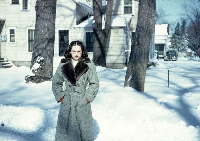 Vintage photo: a woman in a winter coat standing in the snow